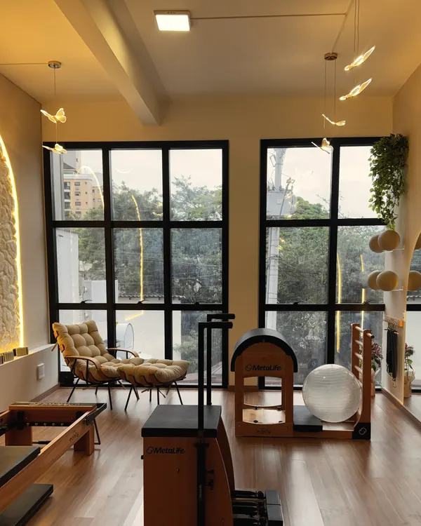 Sala da unidade Beira-Mar com janelões, poltrona, chair, barrel e luminárias de borboleta